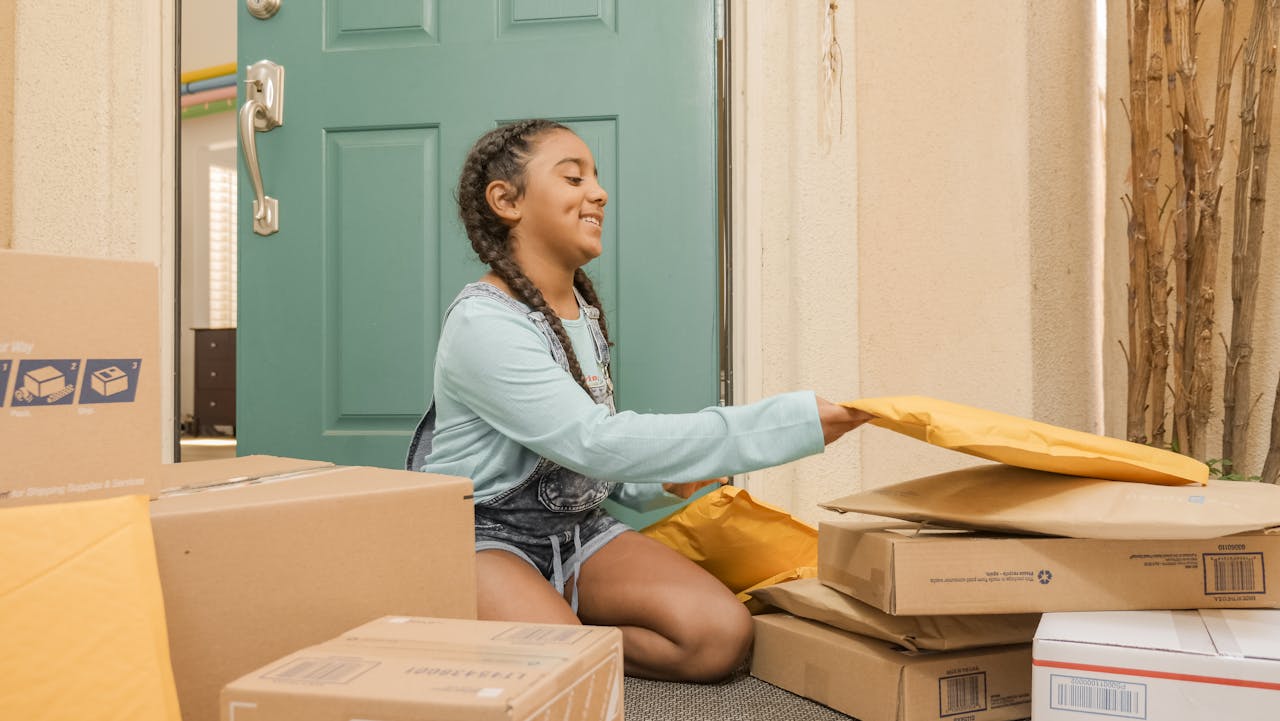 gallery-02 Young girl with braided hair sorting delivery packages on a porch.
